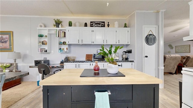 kitchen featuring open shelves, a center island, white cabinetry, light wood-type flooring, and ornamental molding
