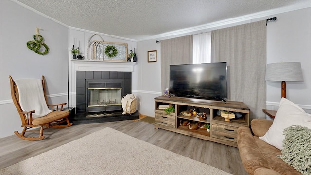 living area with crown molding, a textured ceiling, and a tiled fireplace