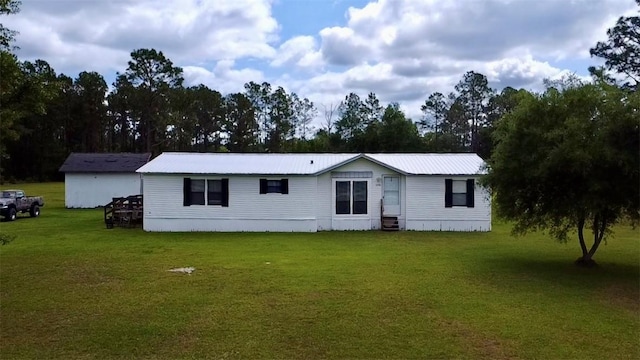 view of front of property with entry steps, metal roof, and a front lawn