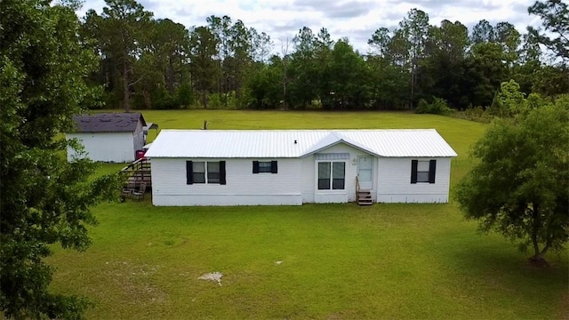 view of front of home featuring metal roof, entry steps, and a front lawn