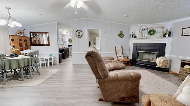 living area with crown molding, a textured ceiling, and ceiling fan with notable chandelier