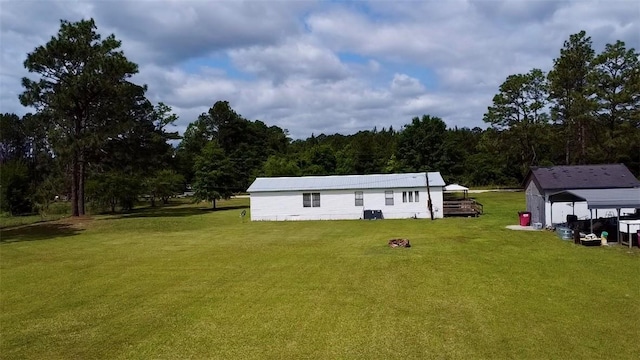 back of house with a yard and a wooded view