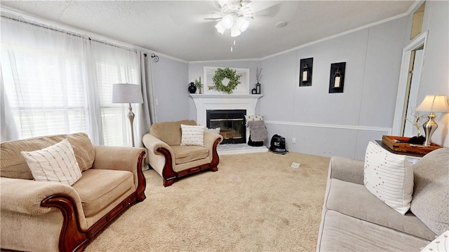 carpeted living area featuring crown molding, a ceiling fan, and a glass covered fireplace