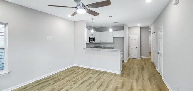 kitchen with ceiling fan, white cabinetry, light stone countertops, light hardwood / wood-style floors, and kitchen peninsula