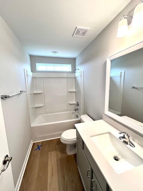 full bath with visible vents, toilet, wood finished floors,  shower combination, and vanity