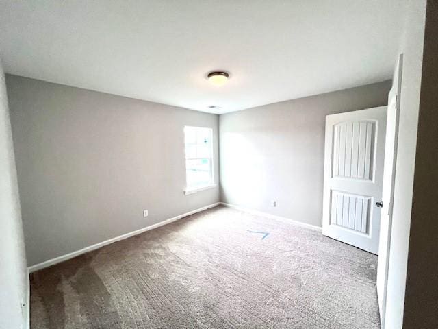 carpeted empty room featuring baseboards