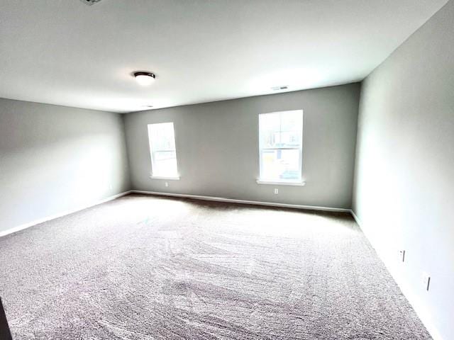 carpeted spare room featuring plenty of natural light and baseboards