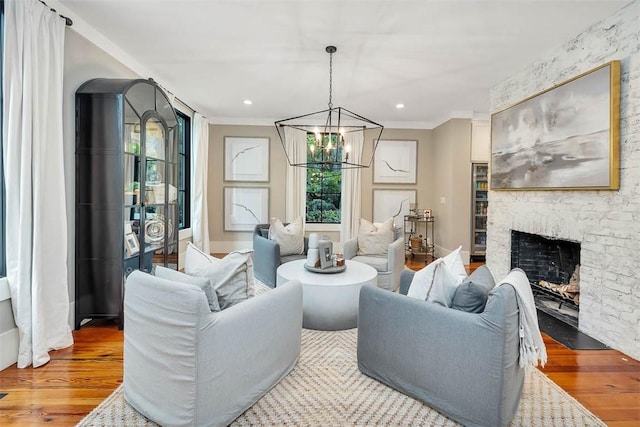 living room with light hardwood / wood-style floors, a stone fireplace, crown molding, and a chandelier