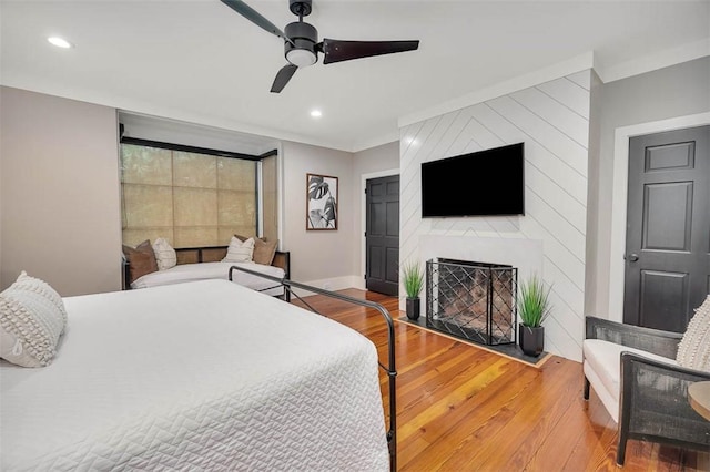 bedroom featuring ceiling fan, wood-type flooring, and a fireplace