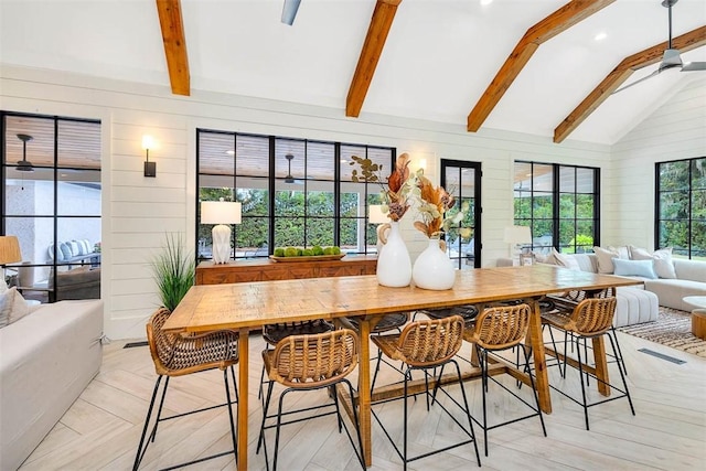 dining room with lofted ceiling with beams, ceiling fan, and wood walls