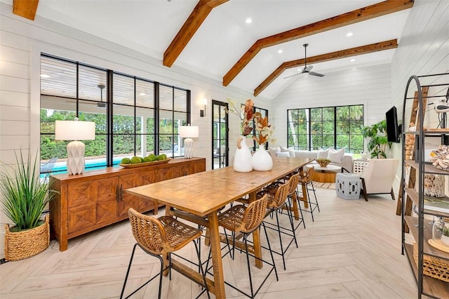 dining room with vaulted ceiling with beams, ceiling fan, wooden walls, and light parquet floors