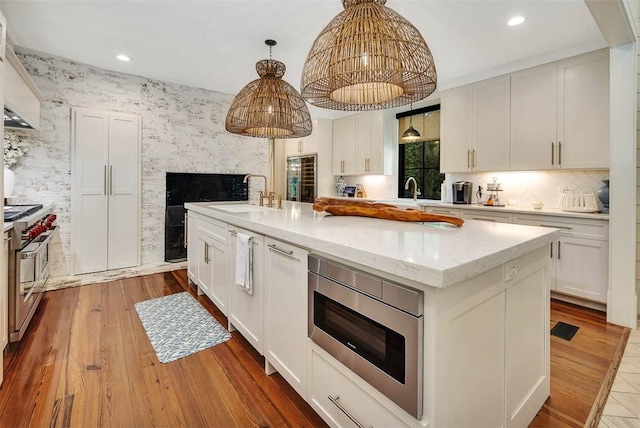 kitchen with white cabinets, sink, light hardwood / wood-style floors, appliances with stainless steel finishes, and a kitchen island