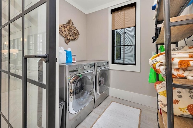 washroom featuring light wood-type flooring, ornamental molding, and separate washer and dryer