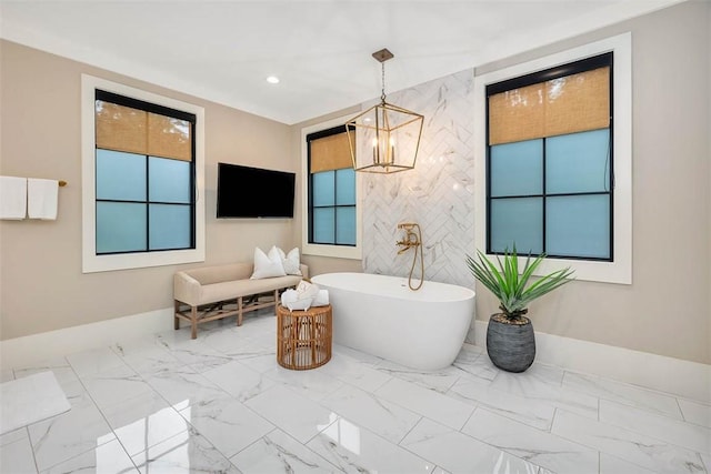 bathroom featuring a tub to relax in, a chandelier, and tile walls