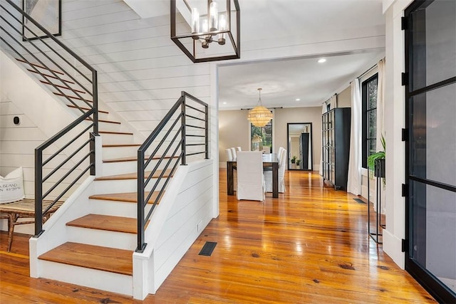 stairs featuring a chandelier and wood-type flooring