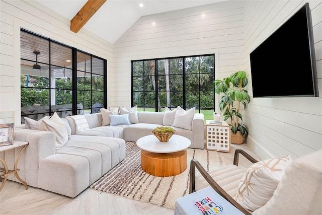 living room featuring wood walls, beamed ceiling, a healthy amount of sunlight, and wood-type flooring