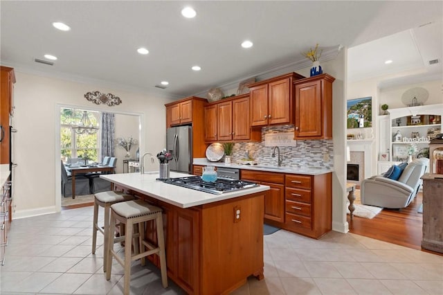 kitchen featuring ornamental molding, appliances with stainless steel finishes, a center island with sink, and a kitchen bar