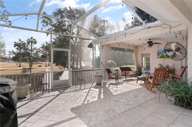 sunroom / solarium with ceiling fan and vaulted ceiling with skylight