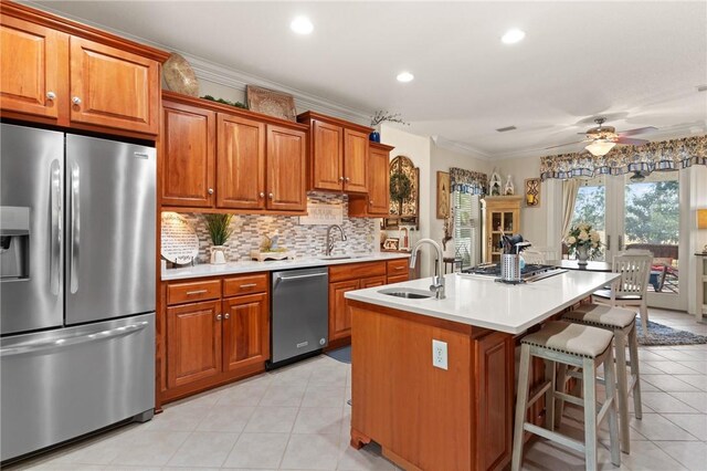 kitchen with stainless steel appliances, ornamental molding, a kitchen island with sink, and sink