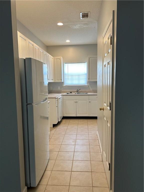 366 Moss Creek Ln, Brunswick, GA 31520 - kitchen featuring white appliances, light countertops, light tile patterned flooring, white cabinets, and a textured ceiling
