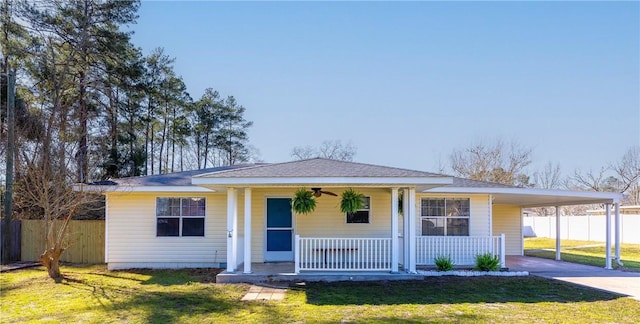 view of front facade featuring a porch, fence, driveway, and a front lawn