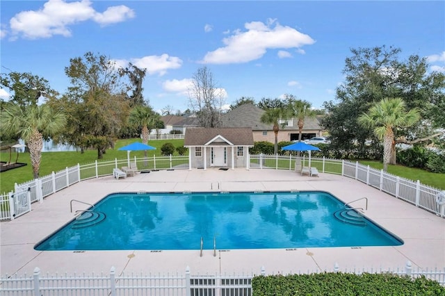 pool featuring a patio, fence, a lawn, and an outdoor structure