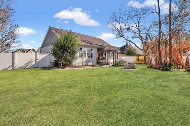 back of property featuring a fire pit, a lawn, and a fenced backyard