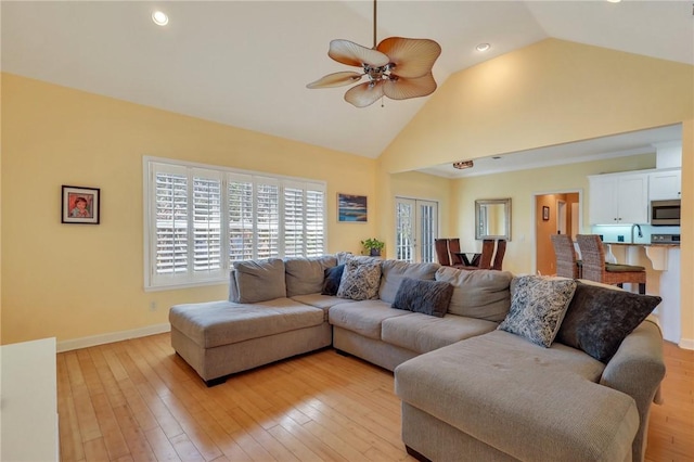 living room with high vaulted ceiling, baseboards, light wood-style floors, and a ceiling fan