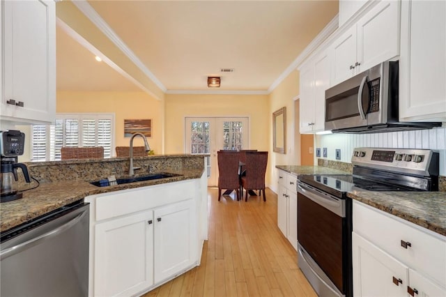 kitchen featuring a sink, white cabinetry, french doors, appliances with stainless steel finishes, and crown molding