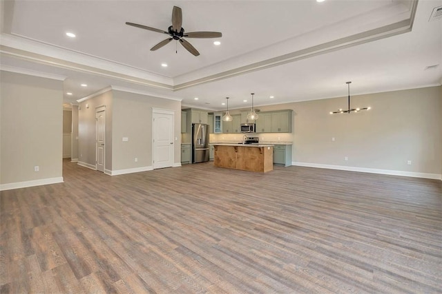 94 Silver Bluff Dr, Brunswick, GA 31523 - unfurnished living room with a raised ceiling, dark wood-style flooring, a chandelier, a ceiling fan, and crown molding