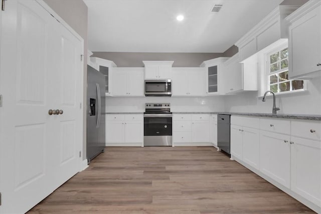 kitchen featuring light stone counters, light wood-type flooring, white cabinetry, and stainless steel appliances