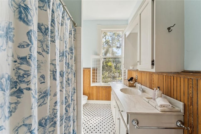 bathroom featuring wood walls, toilet, curtained shower, and vanity