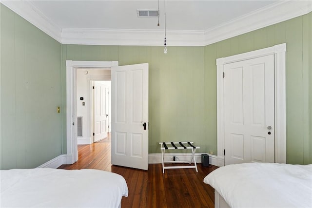 bedroom with crown molding, dark wood-type flooring, and a closet