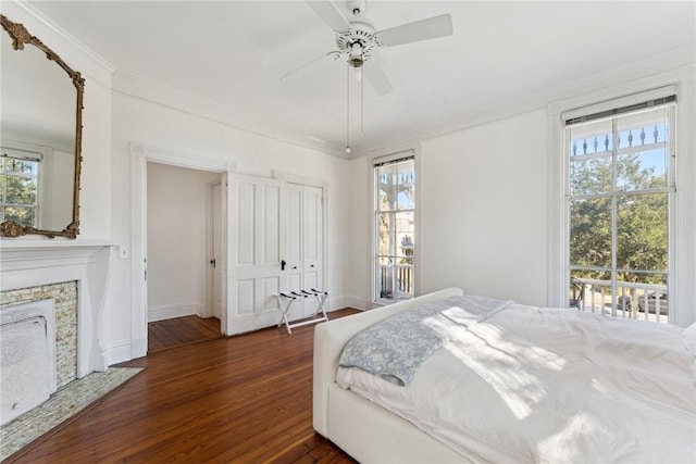 bedroom with crown molding, ceiling fan, a fireplace, access to exterior, and dark hardwood / wood-style floors