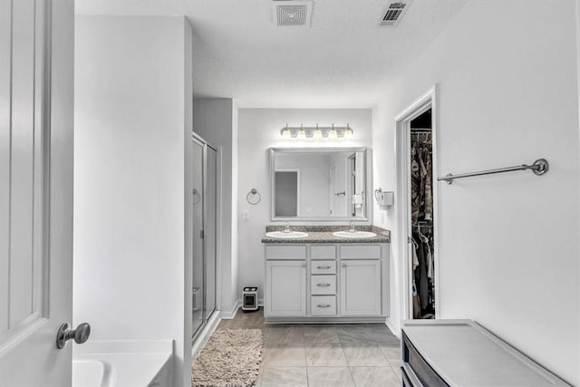 592 Brightleaf Cir, Hinesville, GA 31313 - bathroom with a shower stall, double vanity, a bath, a spacious closet, and a textured ceiling