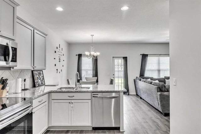 592 Brightleaf Cir, Hinesville, GA 31313 - kitchen featuring appliances with stainless steel finishes, a sink, a peninsula, light wood-type flooring, and light stone counters