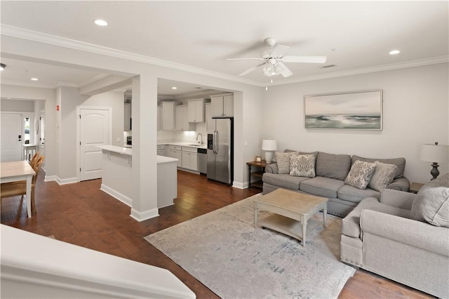 living room featuring dark hardwood / wood-style flooring, ceiling fan, ornamental molding, and sink