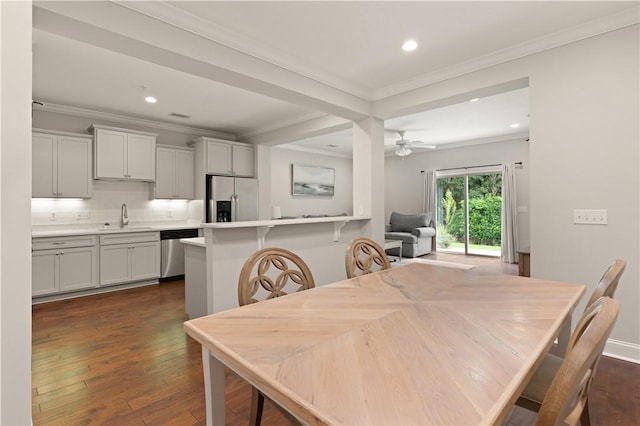 dining space featuring ceiling fan, dark hardwood / wood-style flooring, sink, and crown molding