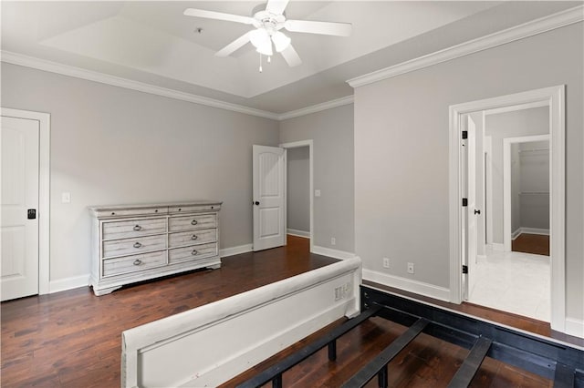 bedroom with ceiling fan, a raised ceiling, ornamental molding, and dark wood-type flooring