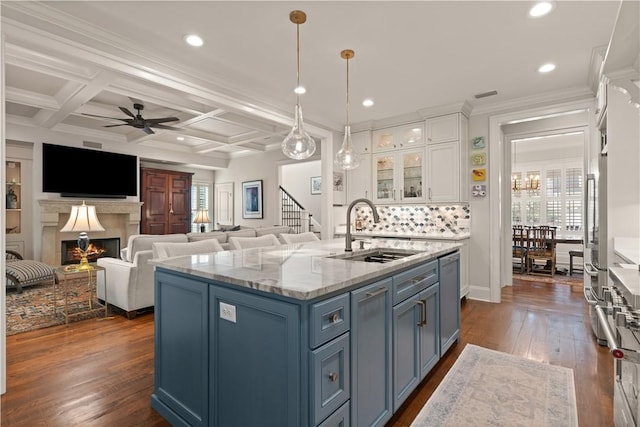 kitchen with blue cabinets, sink, white cabinets, coffered ceiling, and a center island with sink