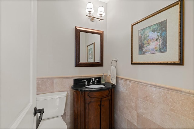 bathroom featuring vanity, tile walls, and toilet