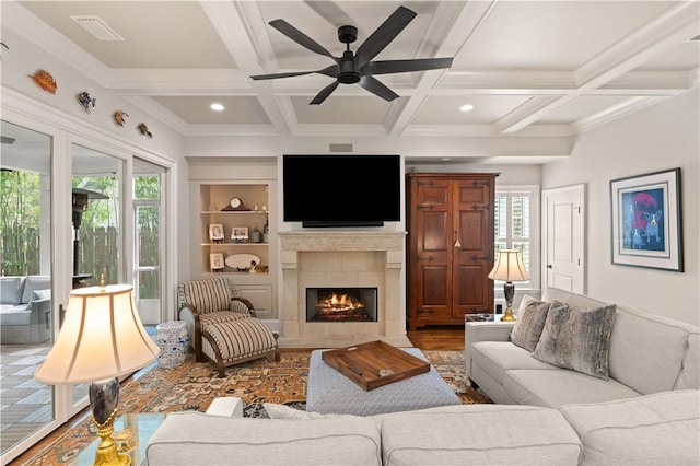 living room with a tiled fireplace, coffered ceiling, built in features, and beamed ceiling