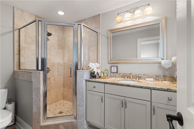 bathroom featuring a shower with door, vanity, and toilet