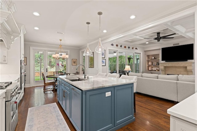 kitchen with decorative light fixtures, an island with sink, sink, stainless steel appliances, and blue cabinetry