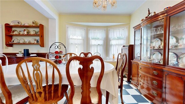 dining room with tile patterned floors, ornamental molding, and an inviting chandelier