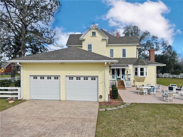 back of house with fence, decorative driveway, a lawn, and a garage