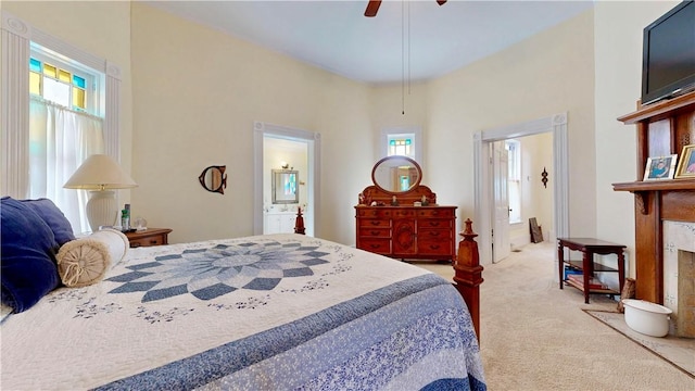 carpeted bedroom featuring a ceiling fan, ensuite bath, and multiple windows