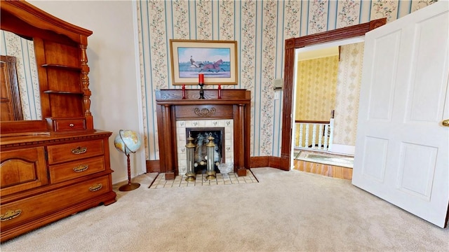 living area featuring a tiled fireplace, baseboards, wallpapered walls, and carpet floors