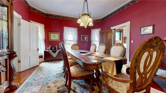 dining space featuring ornamental molding, wood finished floors, and a notable chandelier