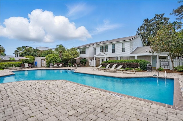 community pool with a patio area and fence